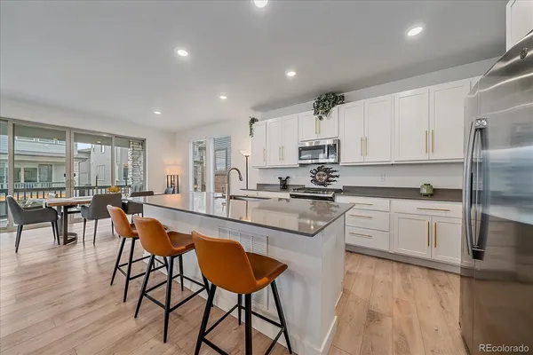 a kitchen with stainless steel appliances granite countertop table chairs sink and cabinets