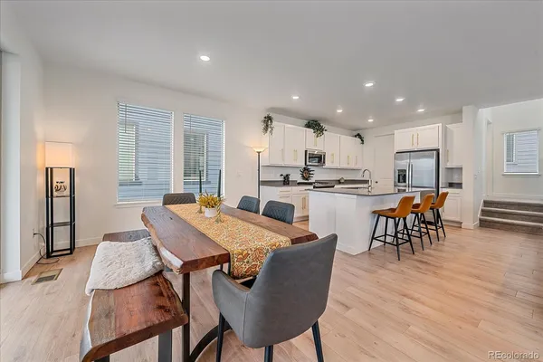 a kitchen with a dining table chairs and refrigerator