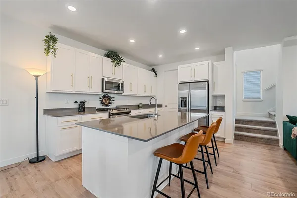 a kitchen with stainless steel appliances kitchen island granite countertop a refrigerator a stove a sink dishwasher and a dining table with wooden floor