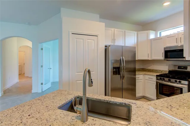 a kitchen with stainless steel appliances granite countertop a refrigerator a stove and a sink
