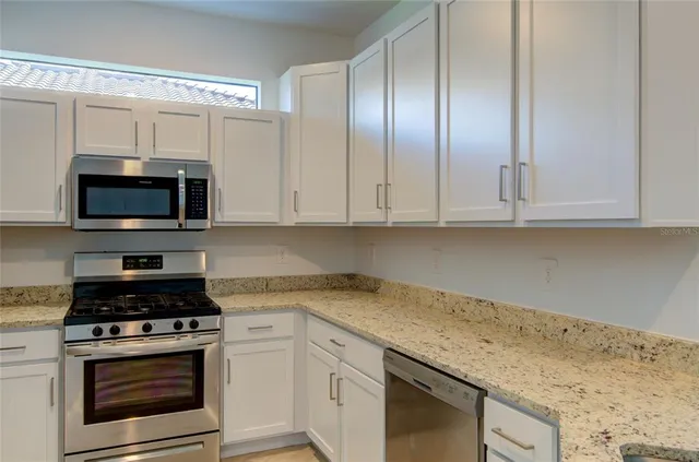 a kitchen with granite countertop white cabinets and stainless steel appliances