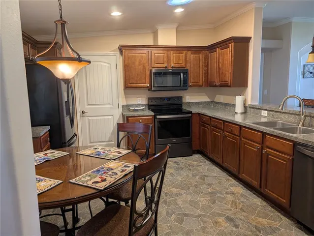 a kitchen with stainless steel appliances granite countertop a sink a stove a refrigerator cabinets and chairs