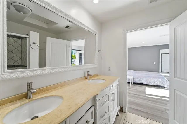 a bathroom with a granite countertop double vanity sink and mirror