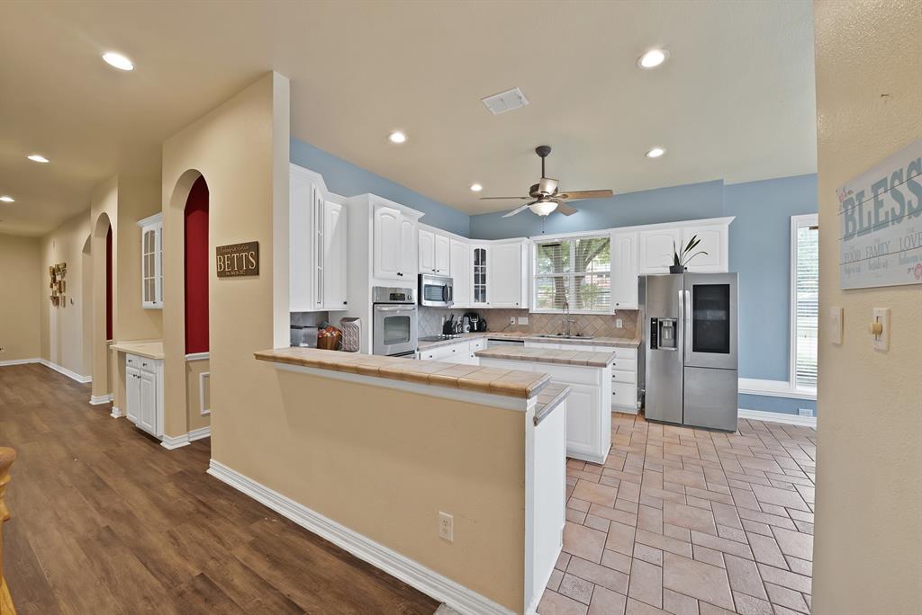 1912 Timber Ridge Court Cedar Hill, TX 75104 - Photo 11 of 35 Kitchen featuring white cabinetry, stainless steel appliances, and a central island with a tile countertop