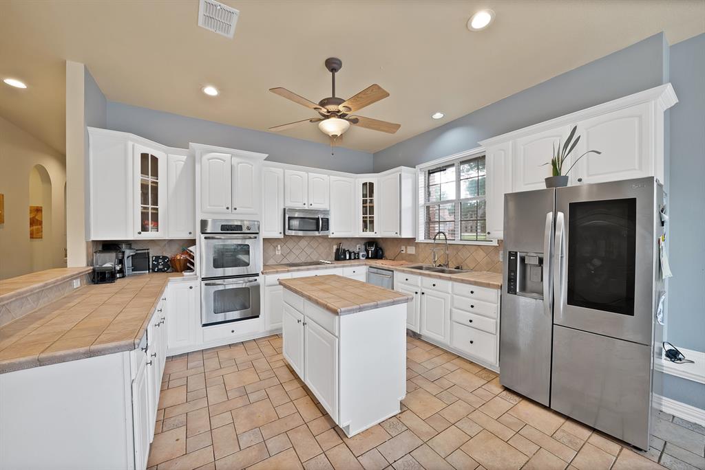 1912 Timber Ridge Court Cedar Hill, TX 75104 - Photo 12 of 35 Spacious kitchen featuring white cabinetry, stainless steel double ovens, and a large stainless steel refrigerator