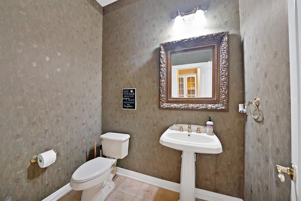 1912 Timber Ridge Court Cedar Hill, TX 75104 - Photo 19 of 35 Pedestal sink with brass-finish faucet, framed mirror, and ornate wall sconce