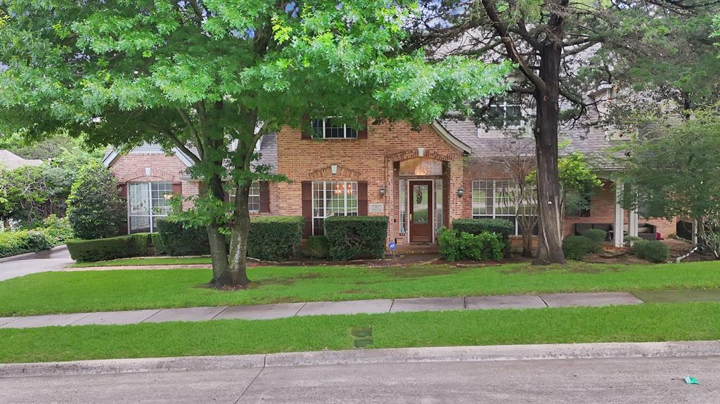 1912 Timber Ridge Court Cedar Hill, TX 75104 - Photo 2 of 35 Brick facade residence featuring a covered front entry, arched architectural details, mature trees, manicured landscaping, and a well-maintained lawn