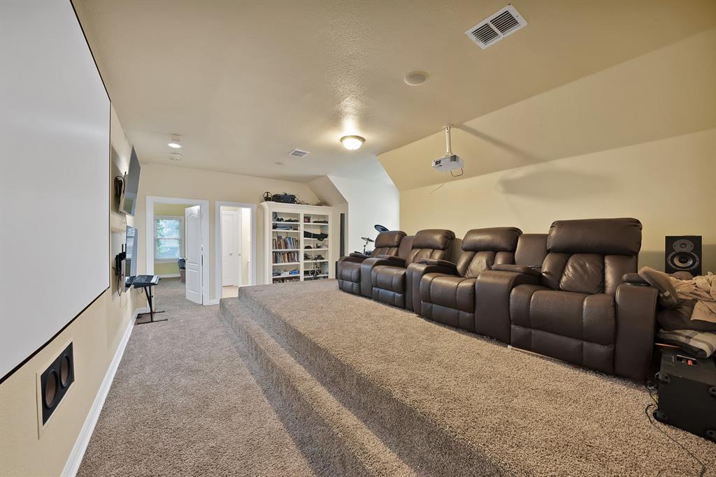 1912 Timber Ridge Court Cedar Hill, TX 75104 - Photo 22 of 35 Dedicated media room featuring a large projection screen, built-in shelving, recessed lighting, and a tiered, carpeted floor