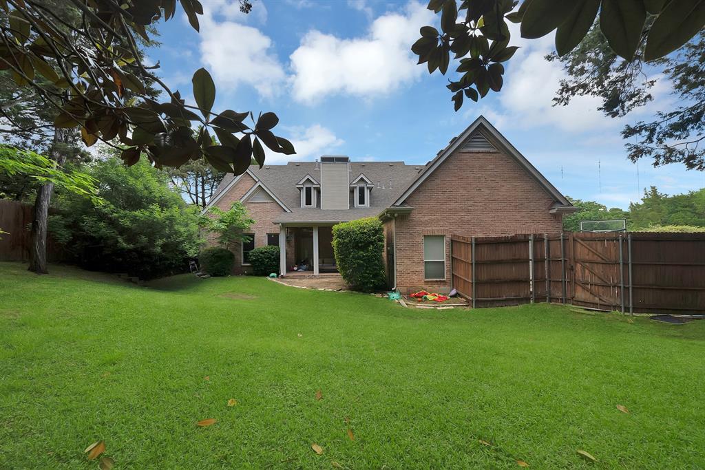 1912 Timber Ridge Court Cedar Hill, TX 75104 - Photo 29 of 35 Expansive backyard featuring a manicured lawn, brick exterior, covered patio with white columns, dormer windows, and a wood privacy fence