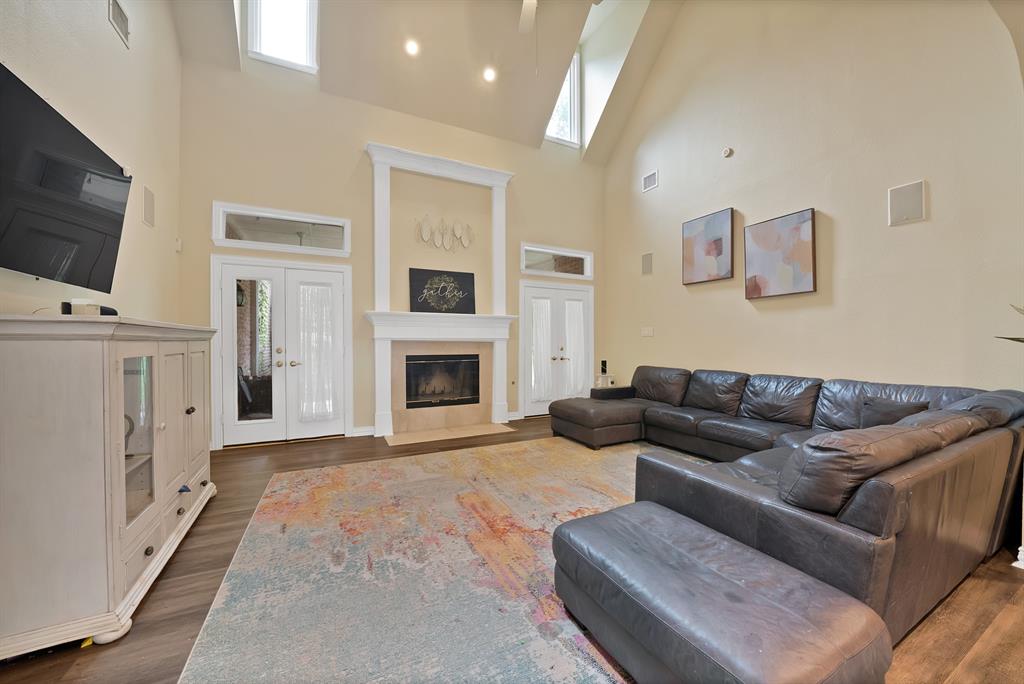 1912 Timber Ridge Court Cedar Hill, TX 75104 - Photo 8 of 35 Open-concept living space featuring vaulted ceilings, wood-finish flooring, and a fireplace with a stone surround