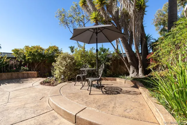 a view of a backyard with a table and chairs under an umbrella