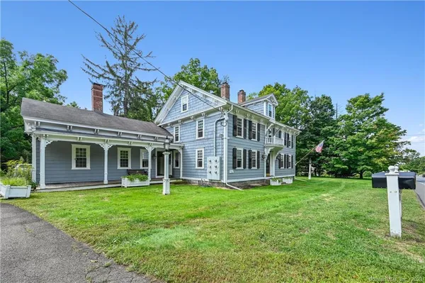 a front view of a house with a garden and trees