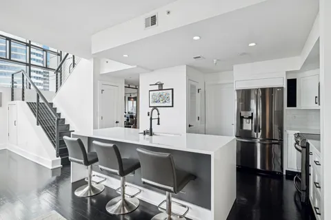 a kitchen with stainless steel appliances a dining table chairs and refrigerator