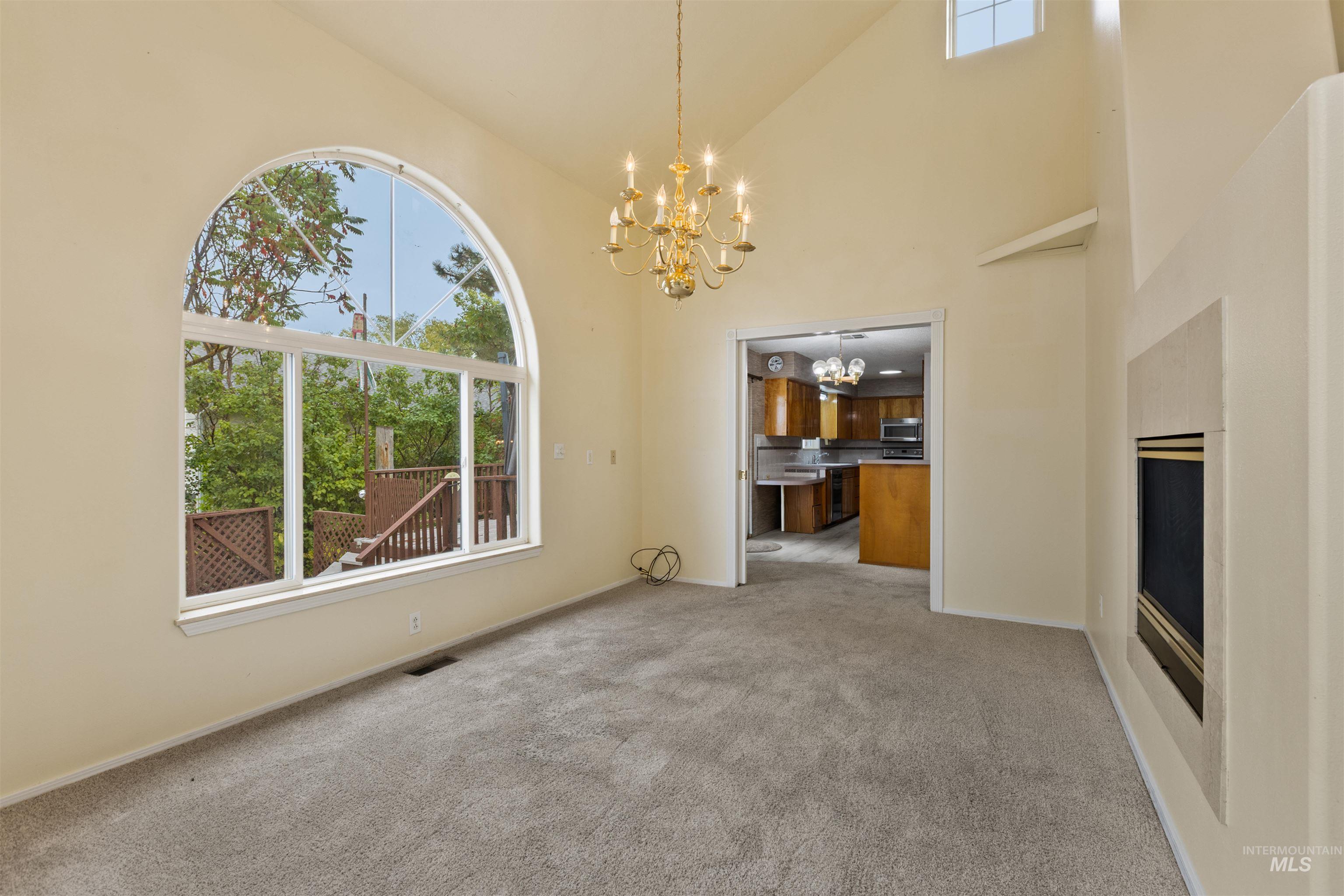 9948 Ash Lane Payette, ID 83661 - Photo 11 of 34 Unfurnished living room featuring carpet, high vaulted ceiling, and a chandelier