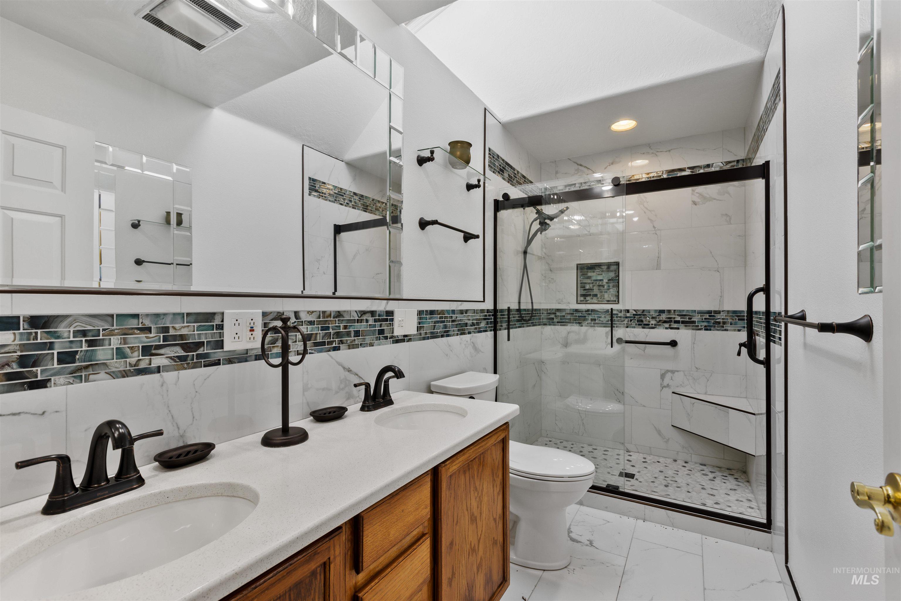 9948 Ash Lane Payette, ID 83661 - Photo 21 of 34 Full bath with double vanity, a marble finish shower, light marble finish flooring, tile walls, and backsplash
