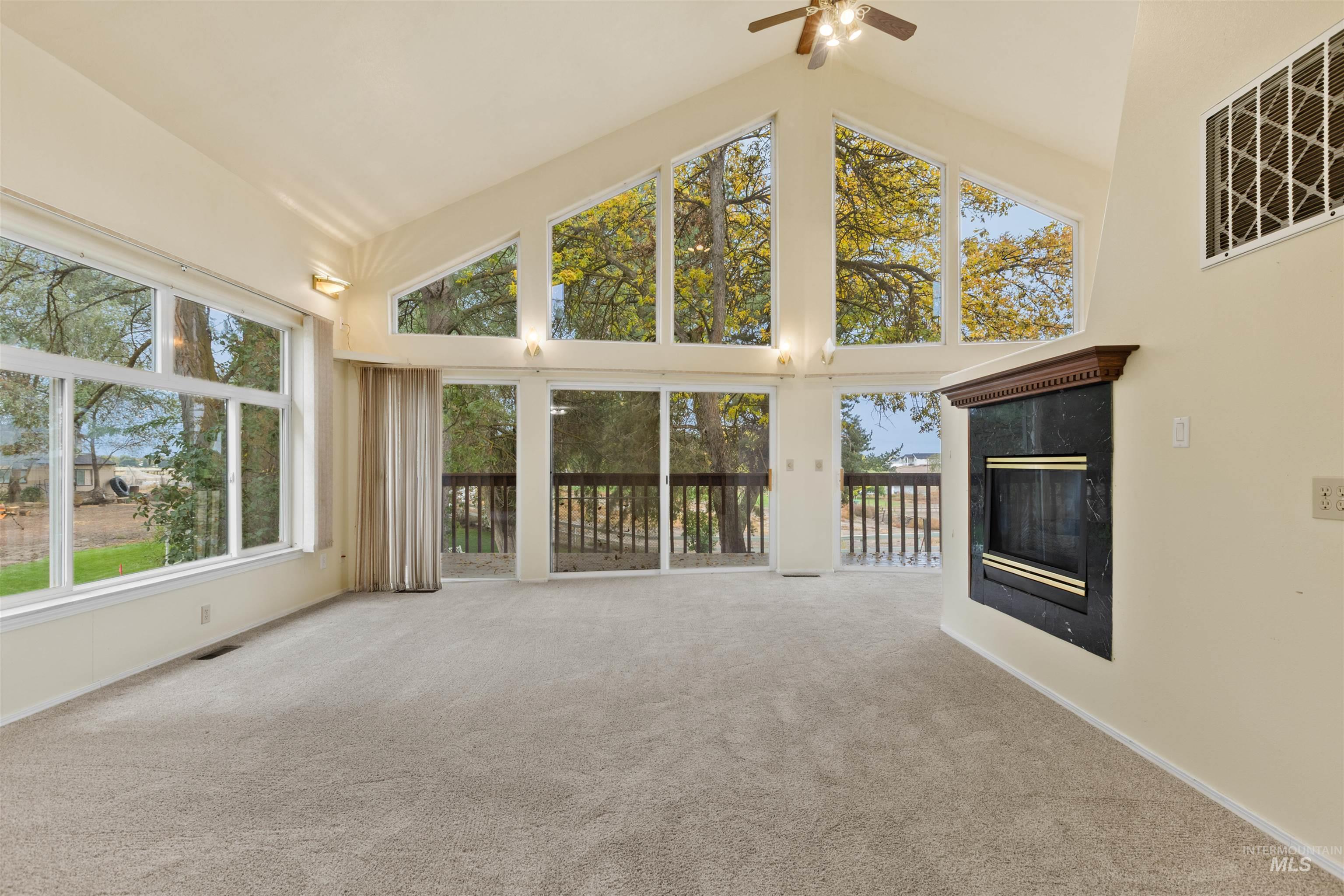 9948 Ash Lane Payette, ID 83661 - Photo 6 of 34 Unfurnished living room featuring high vaulted ceiling, a premium fireplace, plenty of natural light, carpet, and a ceiling fan