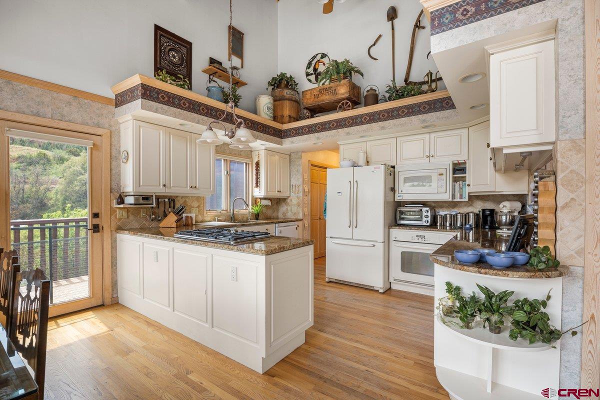 2490 County Road 17 Ridgway, CO 81432 - Photo 14 of 26 a kitchen with stainless steel appliances granite countertop a refrigerator a stove and white cabinets with wooden floor