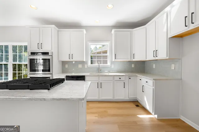 a kitchen with stainless steel appliances granite countertop a stove a sink and white cabinets