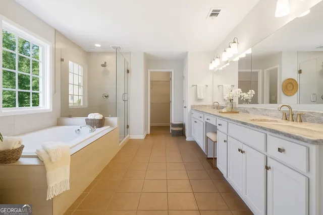 a large bathroom with a double vanity sink a large mirror and a bathtub