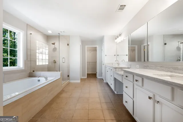 a spacious bathroom with a granite countertop tub sink shower and mirror