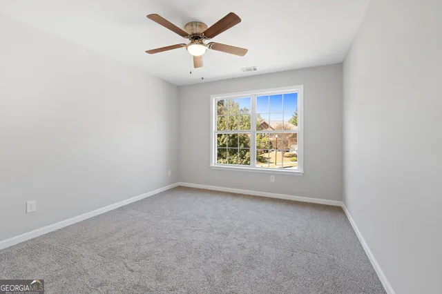 an empty room with windows and ceiling fan