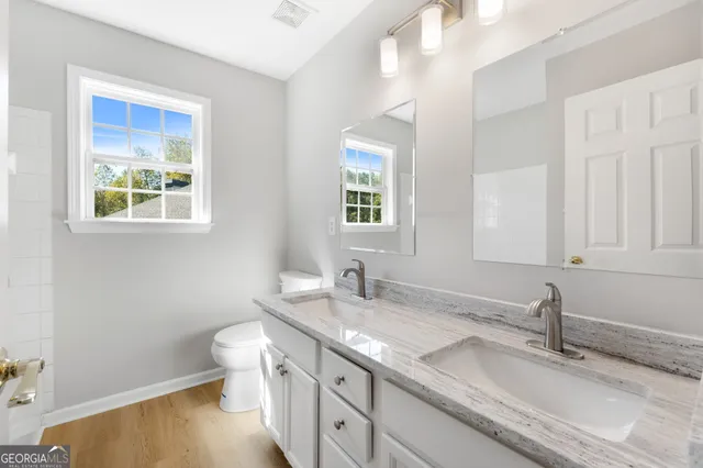 a bathroom with a granite countertop double vanity sink a mirror and a