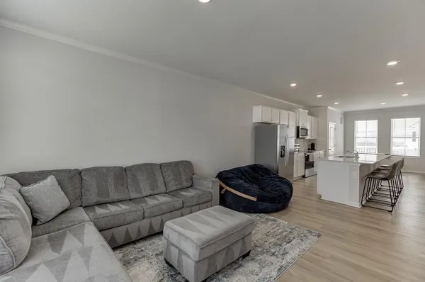a living room with furniture kitchen view and a wooden floor