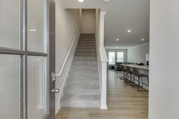 a view of a hallway with couches and dining room with wooden floor