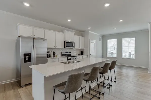 a kitchen with stainless steel appliances a dining table chairs refrigerator and cabinets