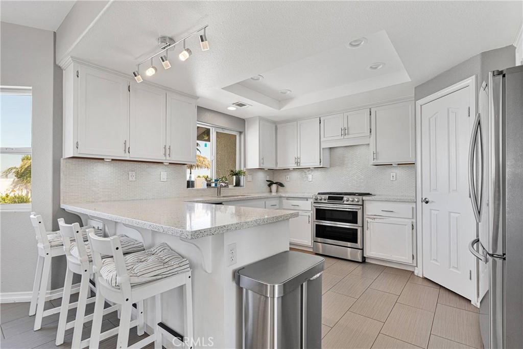 8621 Aster Road Oak Hills, CA 92344 - Photo 16 of 54 a kitchen with stainless steel appliances kitchen island granite countertop a refrigerator and a stove top oven