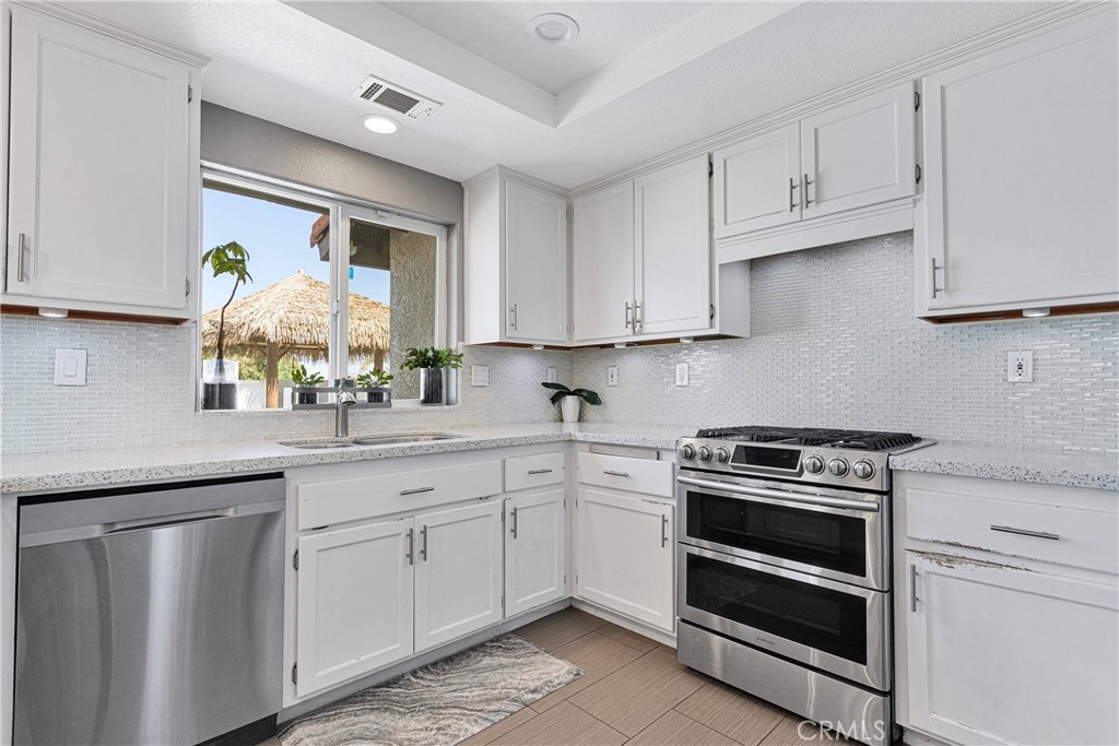8621 Aster Road Oak Hills, CA 92344 - Photo 17 of 54 a kitchen with white cabinets and appliances