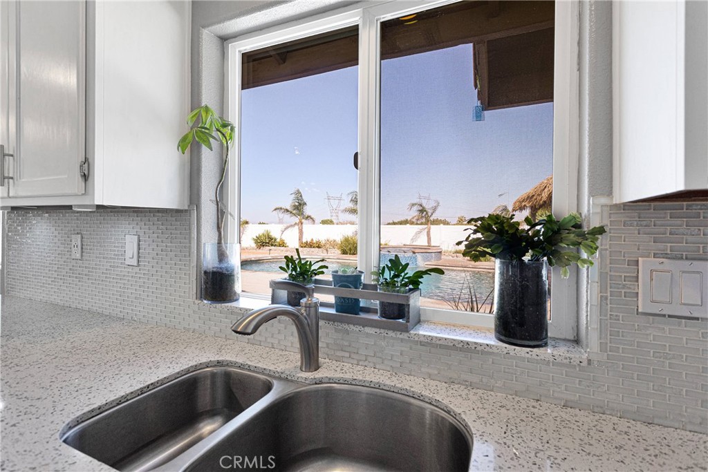 8621 Aster Road Oak Hills, CA 92344 - Photo 19 of 54 a kitchen with a faucet a potted plant on the counter and cabinets