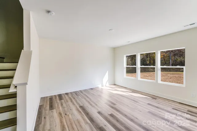 a view of an empty room with wooden floor and windows