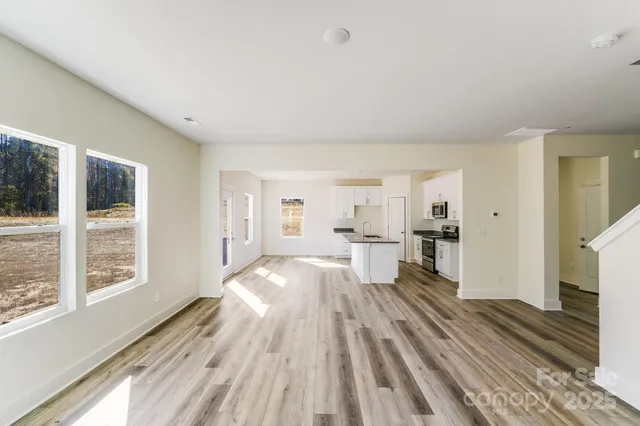 a view of a living room hardwood floor and a kitchen with wooden floor