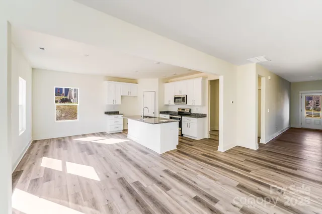 a large white kitchen with kitchen island a sink dishwasher a refrigerator and a stove with wooden floor