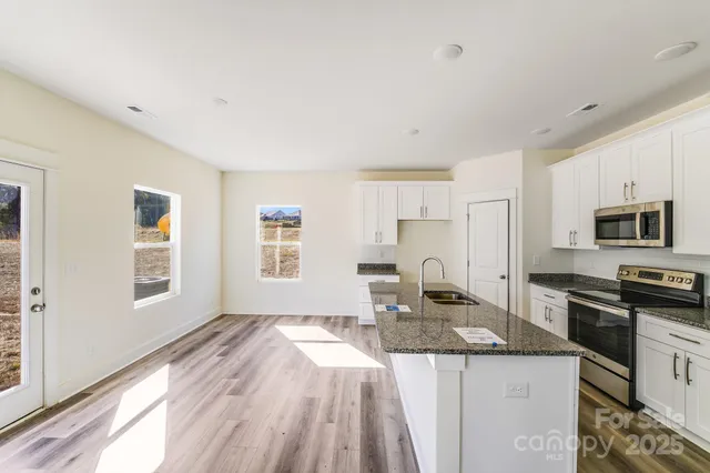 a kitchen with granite countertop a sink stove and refrigerator