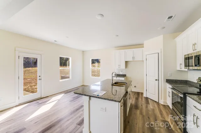 a kitchen with granite countertop a stove refrigerator and wooden floor
