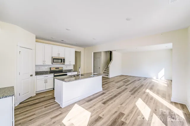 a kitchen with stainless steel appliances a stove a refrigerator a sink dishwasher and a refrigerator with wooden floor