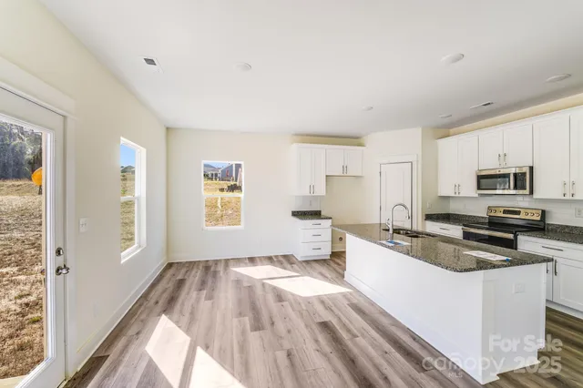 a kitchen with granite countertop a stove a sink and a refrigerator