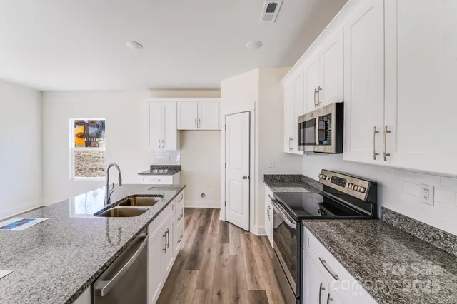 a kitchen with granite countertop a sink a stove and refrigerator