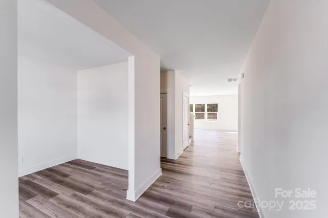 a view of a hallway with wooden floor and closet