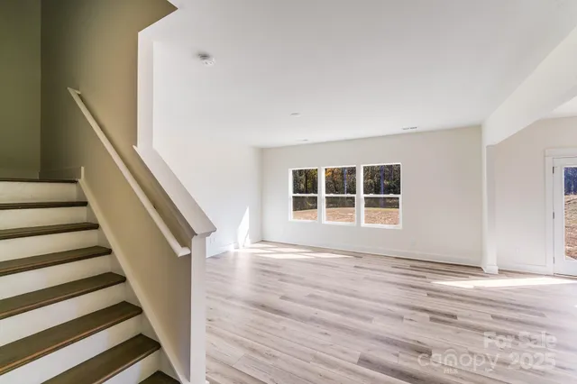 a view of an empty room with wooden floor and windows