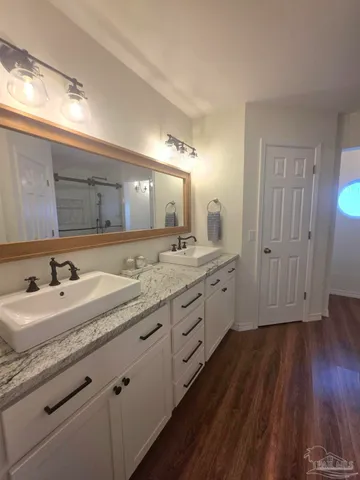 a bathroom with a granite countertop double vanity sink and mirror