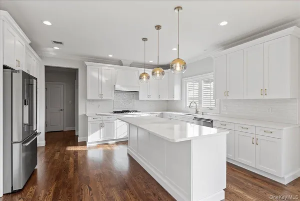 a large kitchen with stainless steel appliances granite countertop a sink a stove a refrigerator and island with wooden floor
