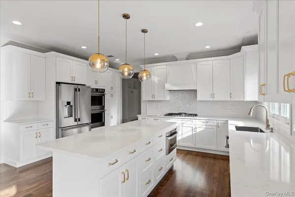 a kitchen with a stove a sink a refrigerator and a wooden floor