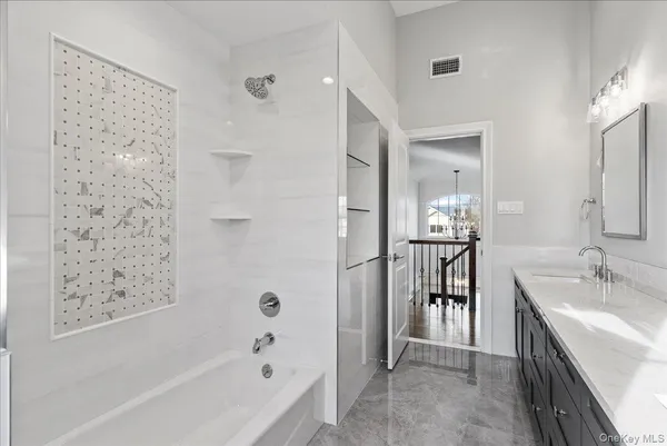 a bathroom with a granite countertop sink mirror and a bathtub