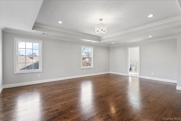 an empty room with wooden floor chandelier and windows