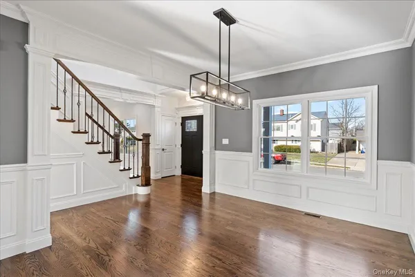 a hallway with wooden floor chandelier and entryway