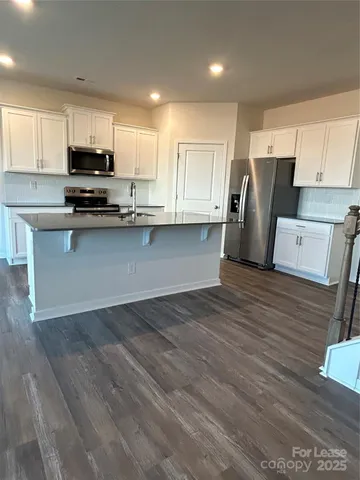 a kitchen with granite countertop a refrigerator and a stove top oven