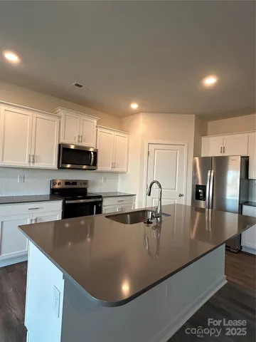 a kitchen with stainless steel appliances granite countertop a sink a stove top oven a counter space and cabinets